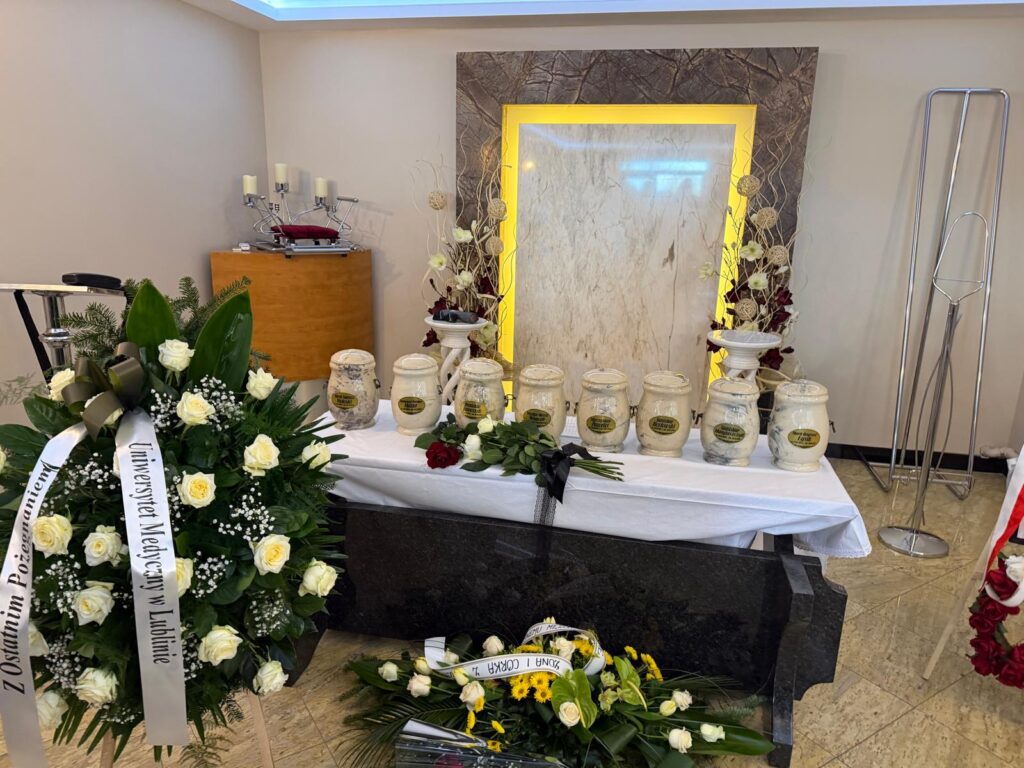 Urny z prochami podczas uroczystej ceremonii pożegnalnej donatorów. Widoczny wieniec z szarfą od Uniwersytetu Medycznego w Lublinie.