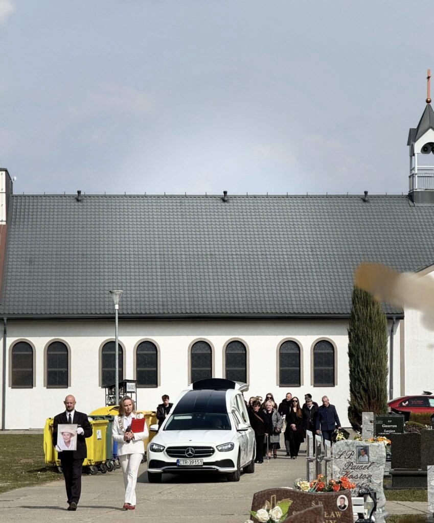 Mistrzyni ceremonii pogrzebowej Aneta Dobroch prowadzi kondukt żałobny podczas pogrzebu świeckiego przed kaplicą cmentarną.